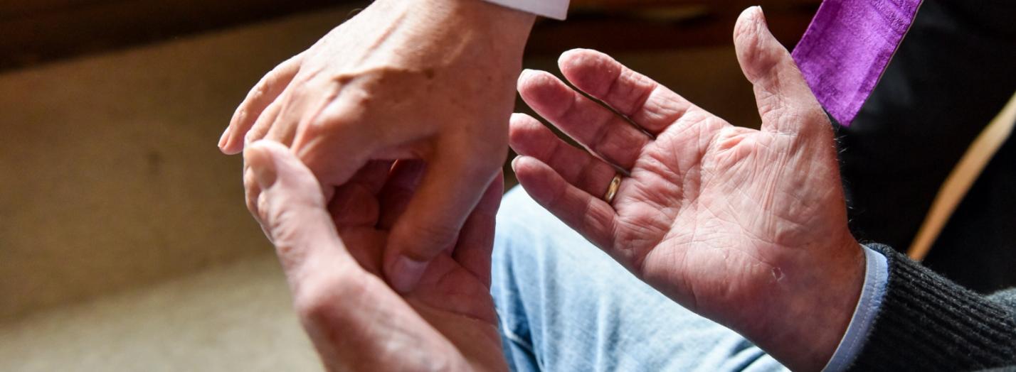 Ein Pfarrer besucht am 8. September 2017 in Bonn einen Kranken zu Hause in seiner Wohnung und spendet die Krankensalbung. Mit Salböl zeichnet der Priester ein Kreuz in die Handflächen des Mannes.